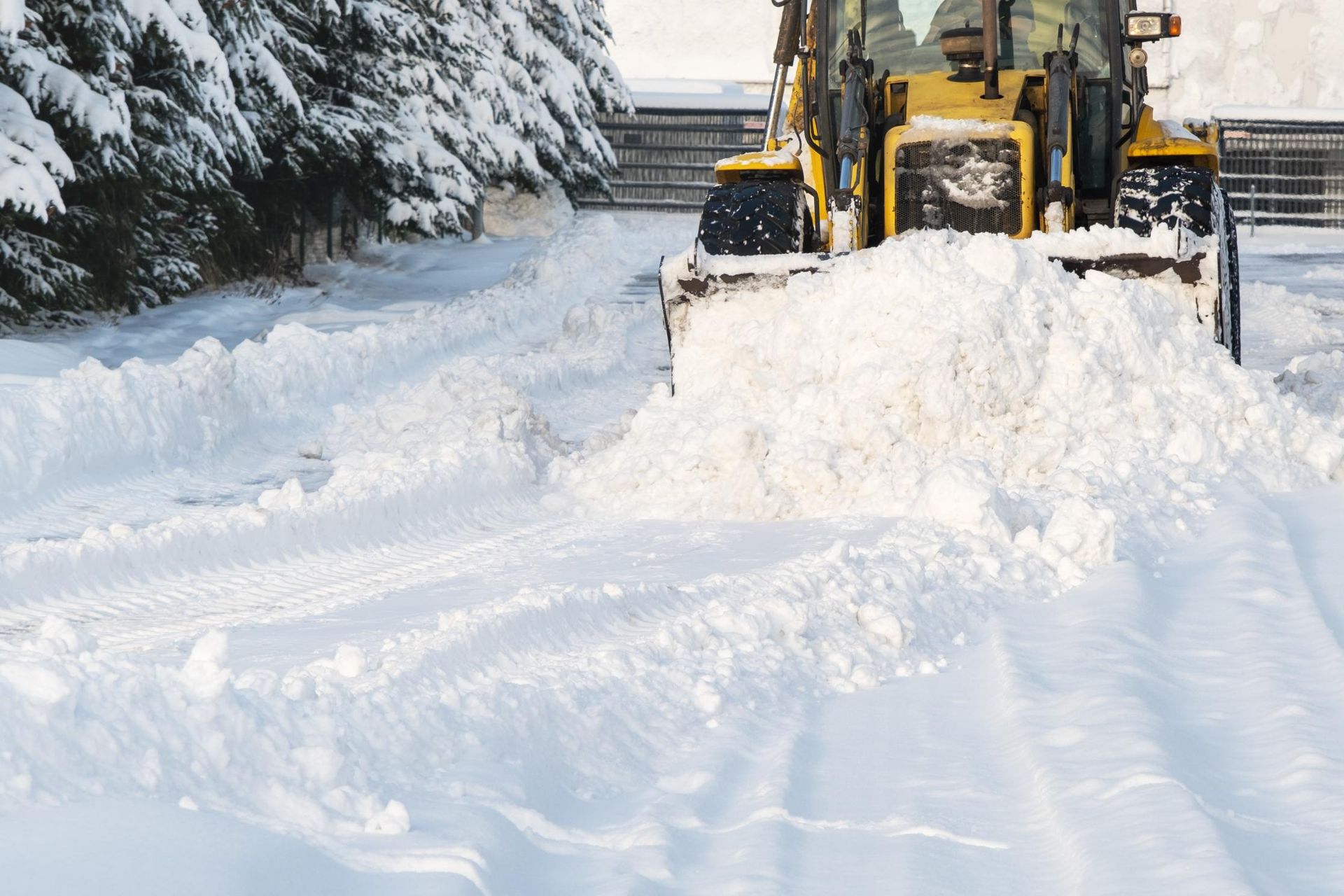 A snow plow is clearing snow from a snow covered road.
