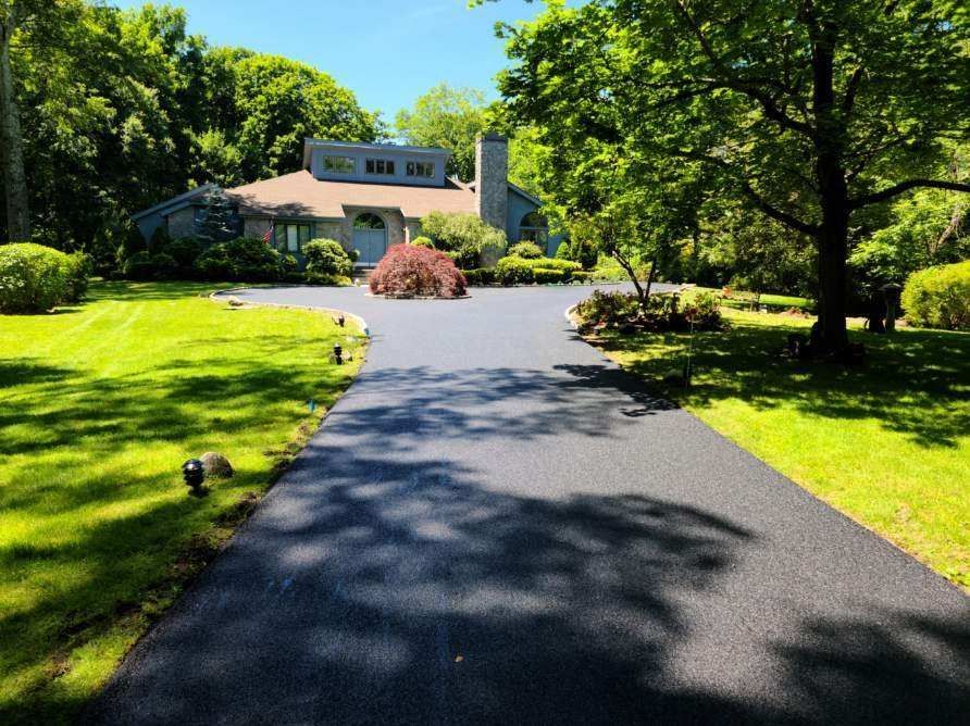 A driveway leading to a large house surrounded by trees.