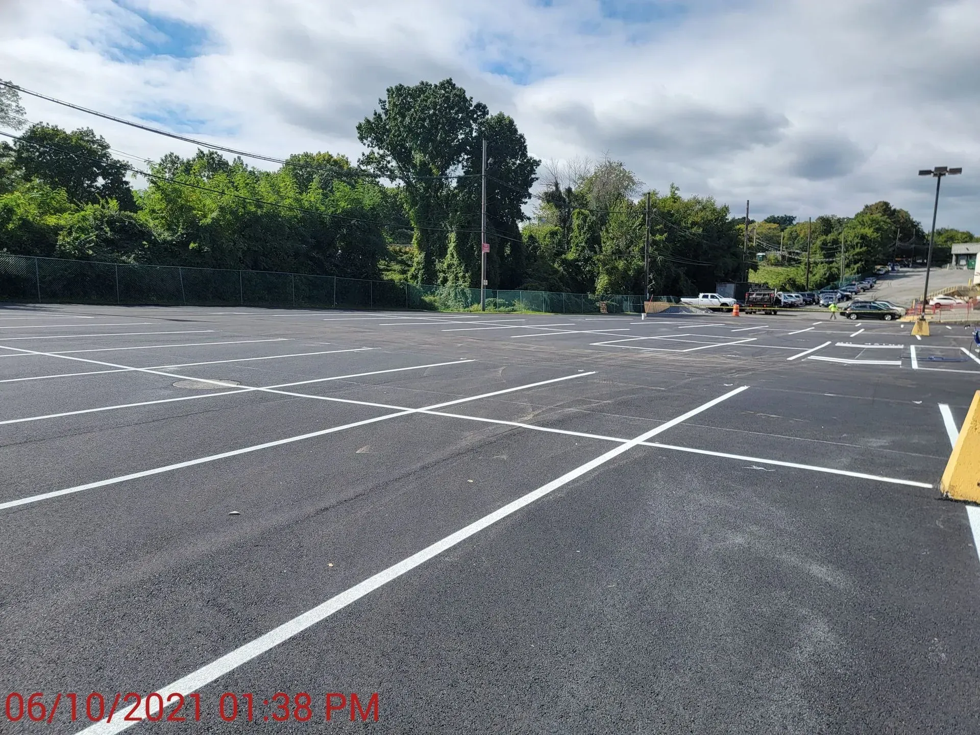 A parking lot with white lines and trees in the background.