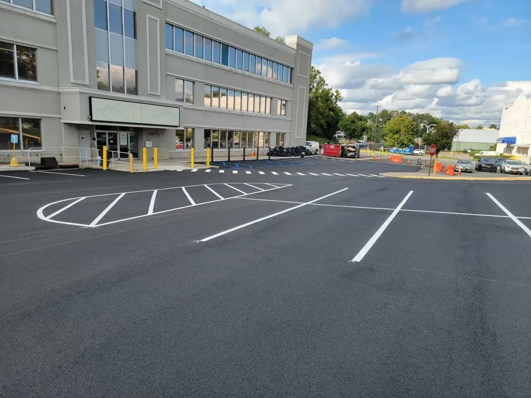 A parking lot in front of a large building with a handicapped parking spot.