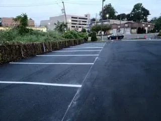 A parking lot with white lines on it and a building in the background.