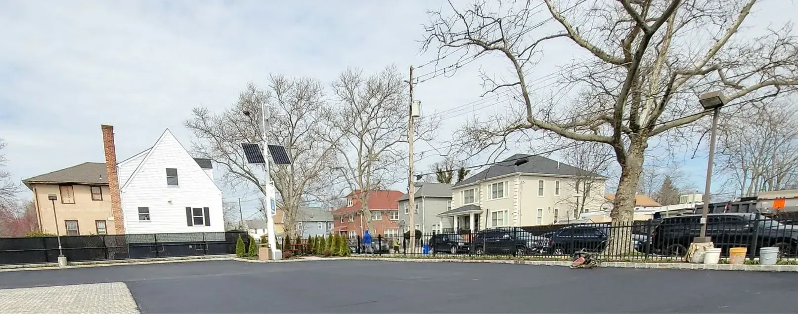 A parking lot with a lot of cars parked in front of a row of houses.