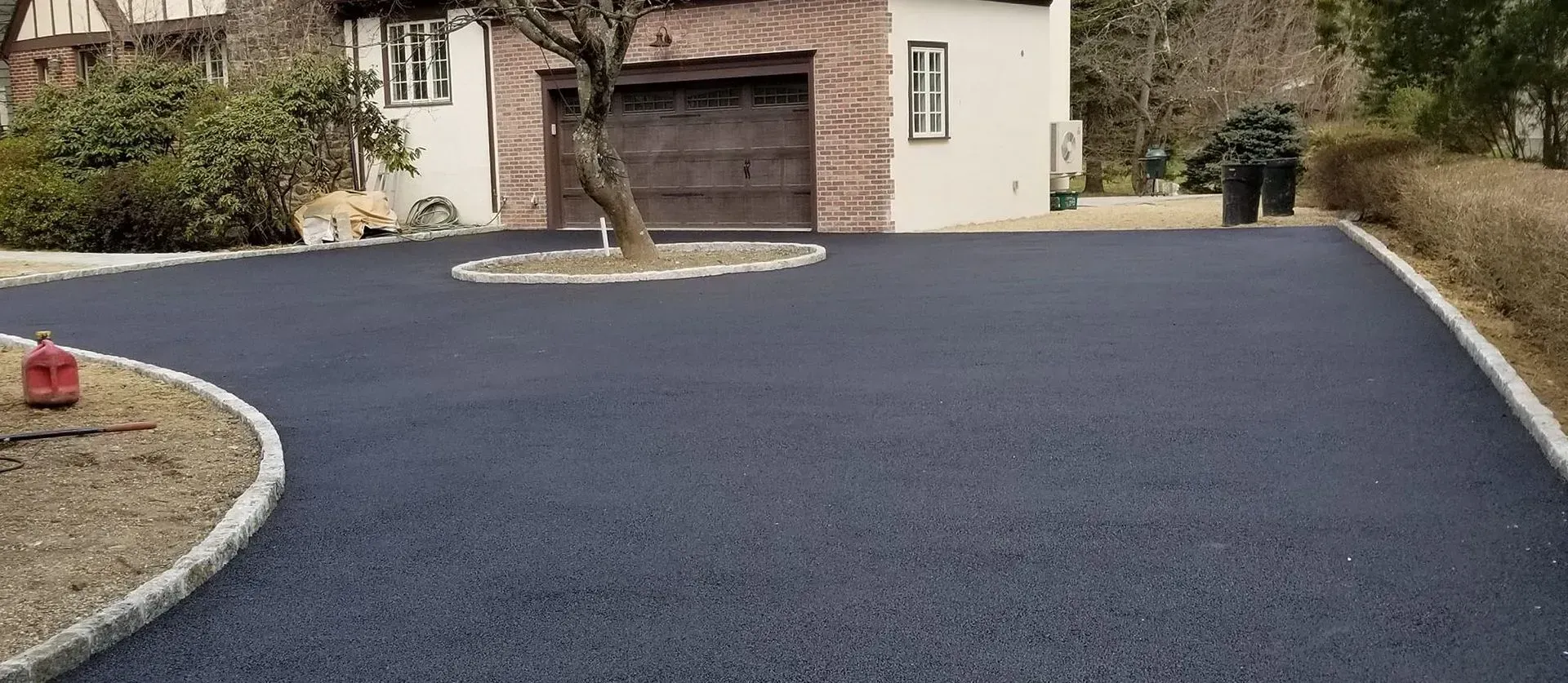 A driveway with a tree in the middle is being built in front of a house.