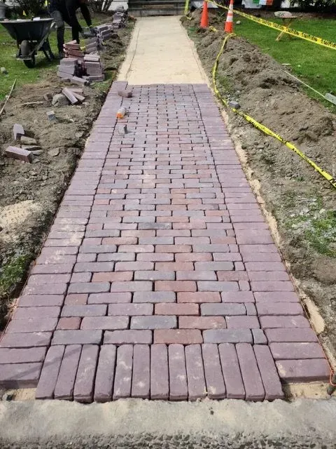 A brick walkway is being built in the dirt.