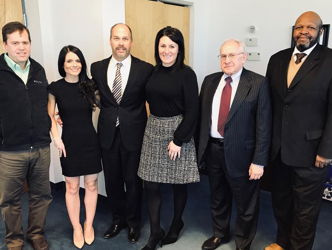 White kitchen with stainless steel appliances, a center island, and overhead lighting.