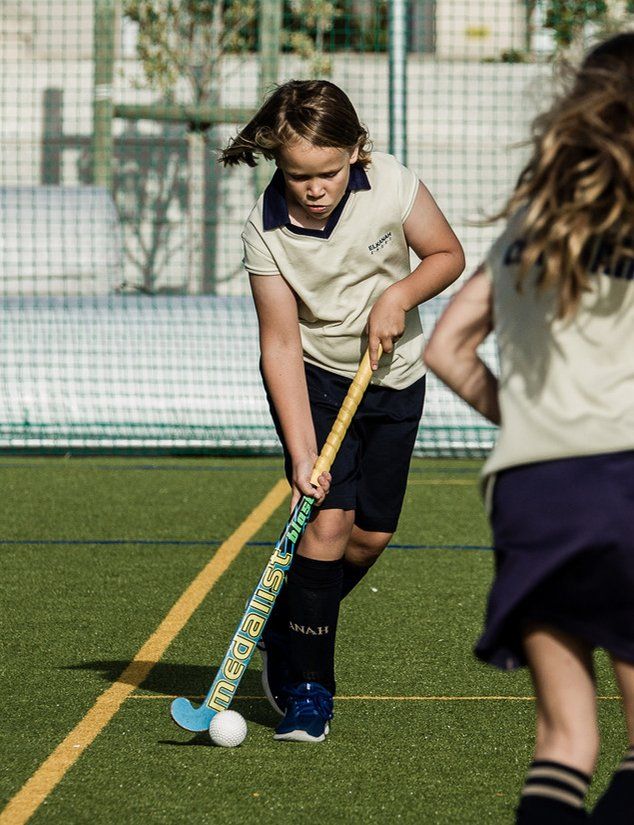 a young girl is playing field hockey on a field .