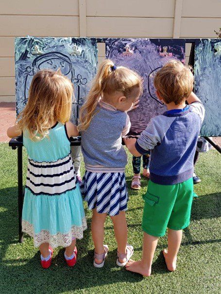 three children are standing in front of a painting .