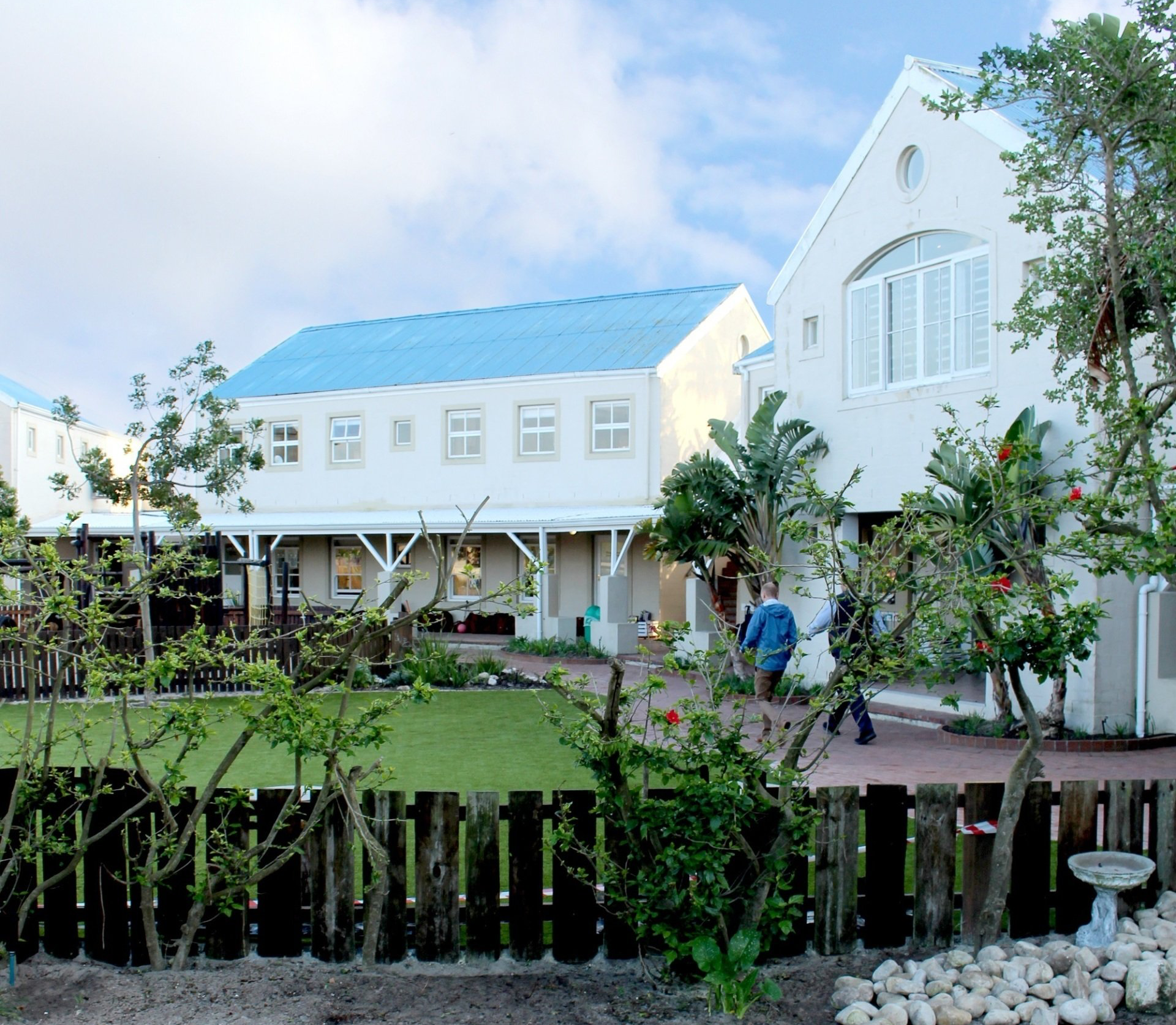 A white house with a blue roof and a black fence
