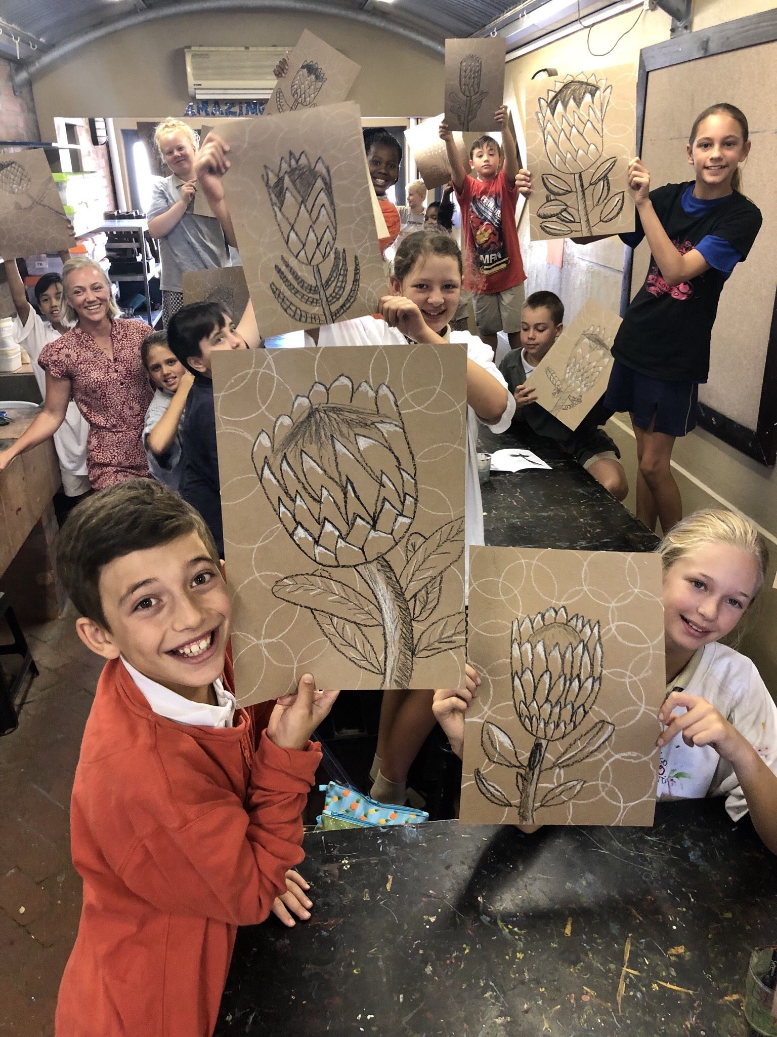 a group of children are holding up cardboard drawings of flowers .
