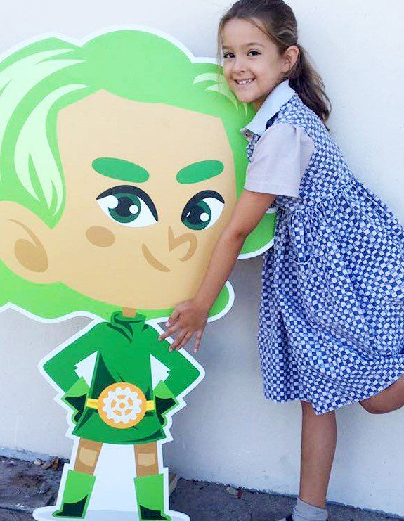 a little girl is standing next to a cardboard cutout of a cartoon character with green hair