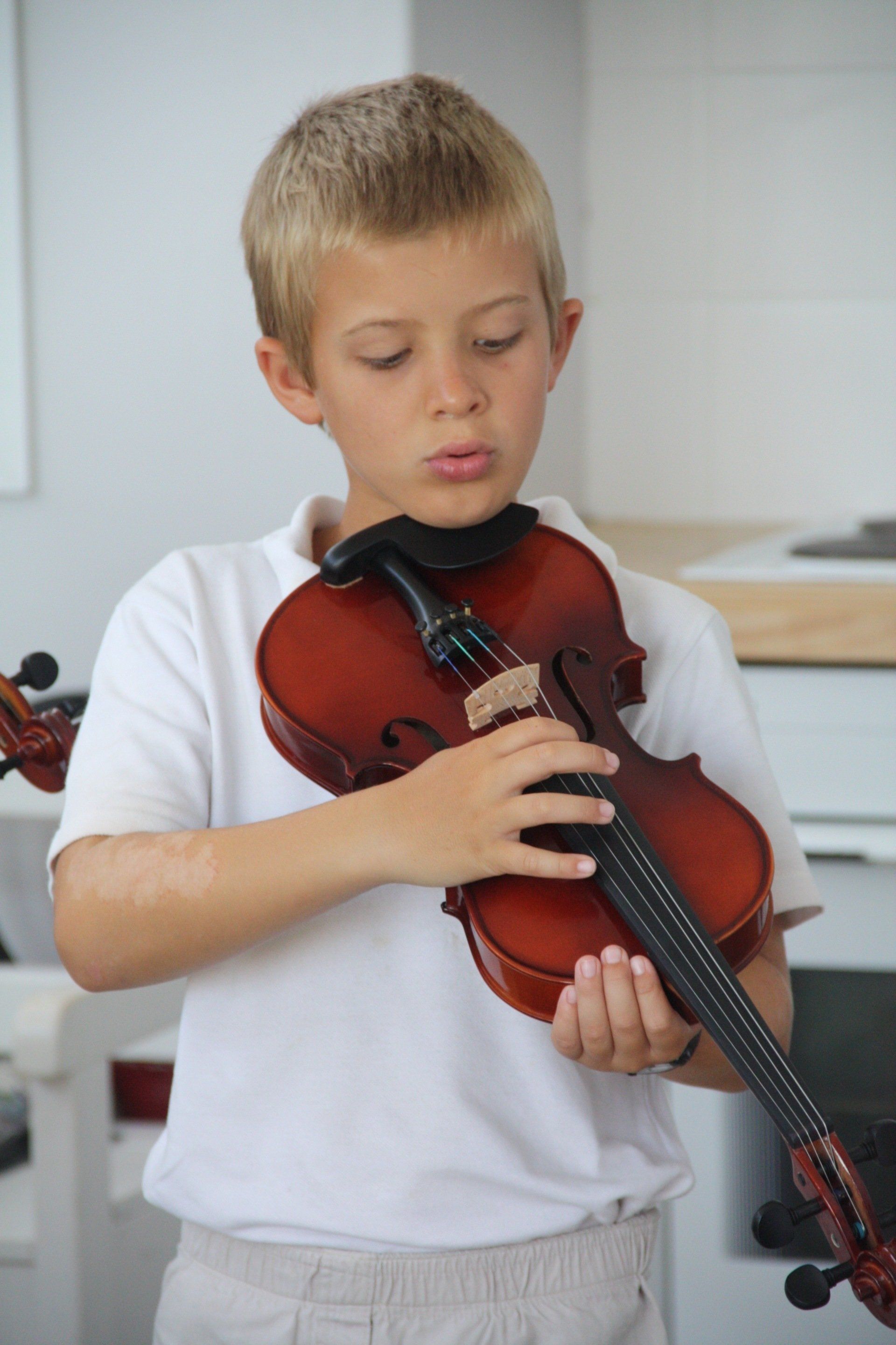 a young boy in a white shirt is playing a violin