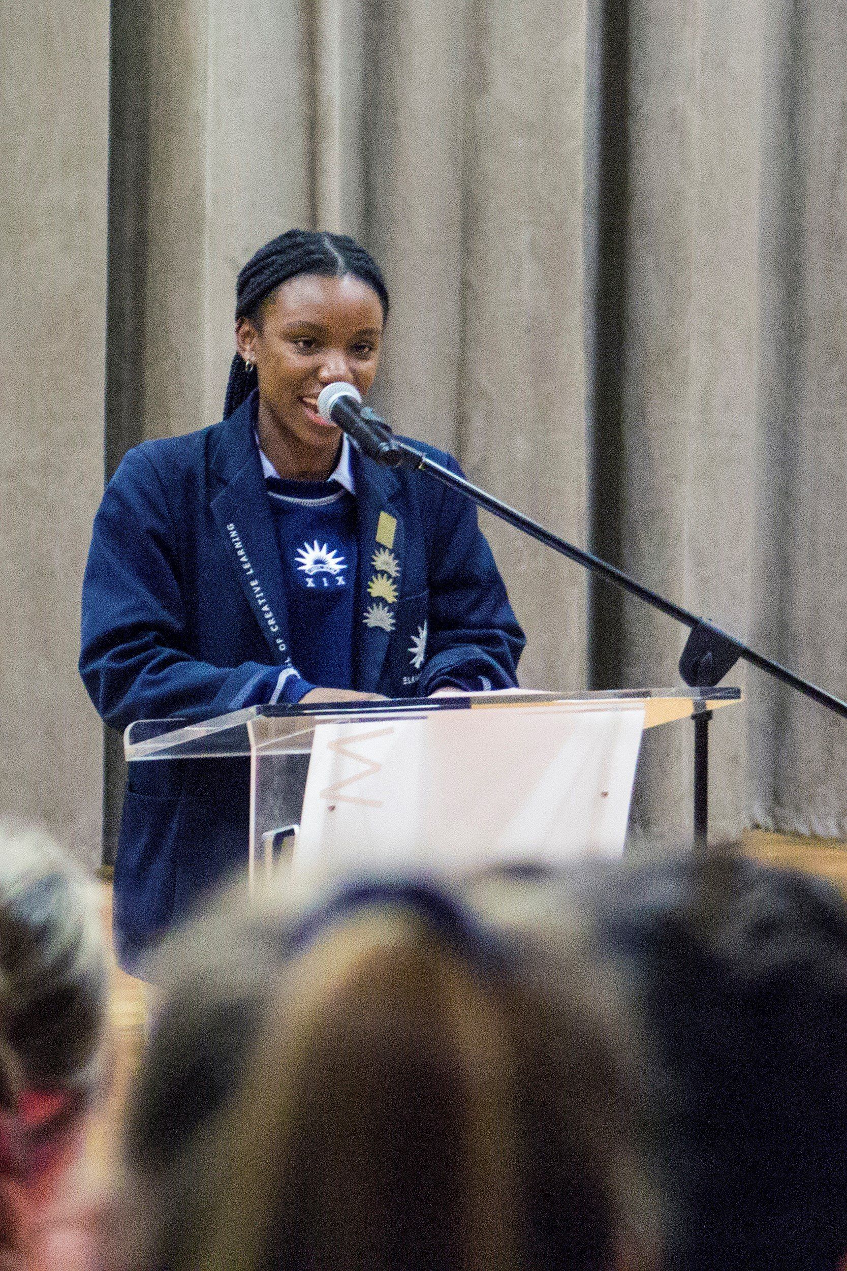 a girl is standing at a podium speaking into a microphone .