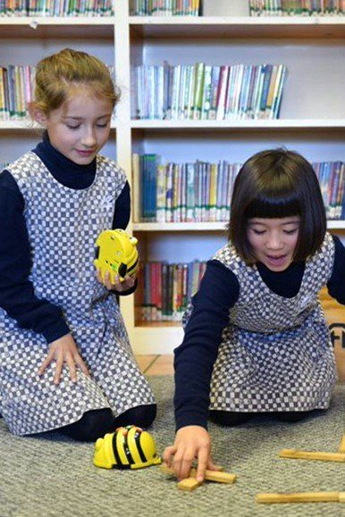 two young girls are playing with a toy bee in a library