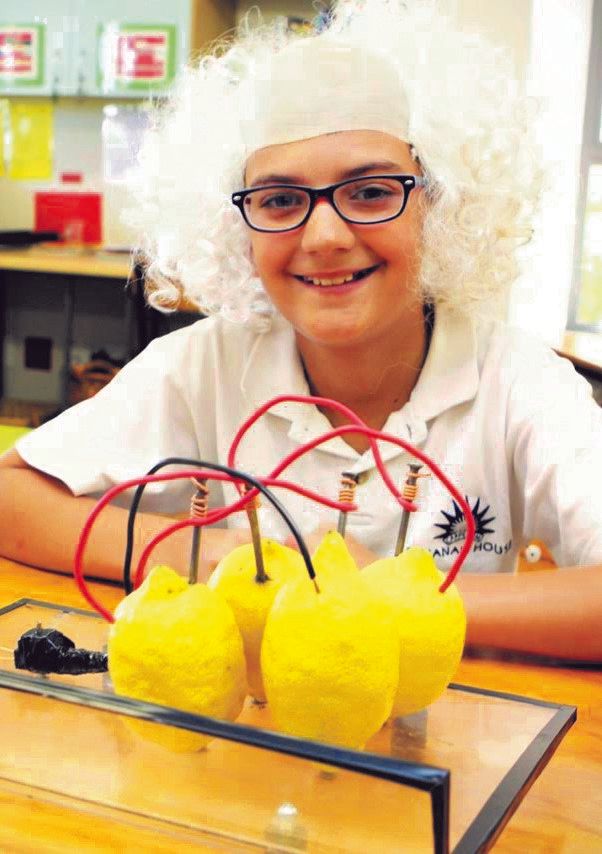 a young boy wearing a white wig and glasses is sitting at a table with yellow lemons and wires .