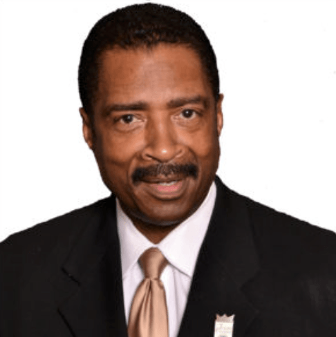 A man in a suit and tie is smiling for the camera