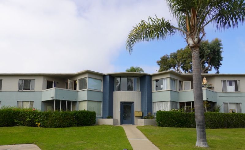 A large apartment building with a palm tree in front of it