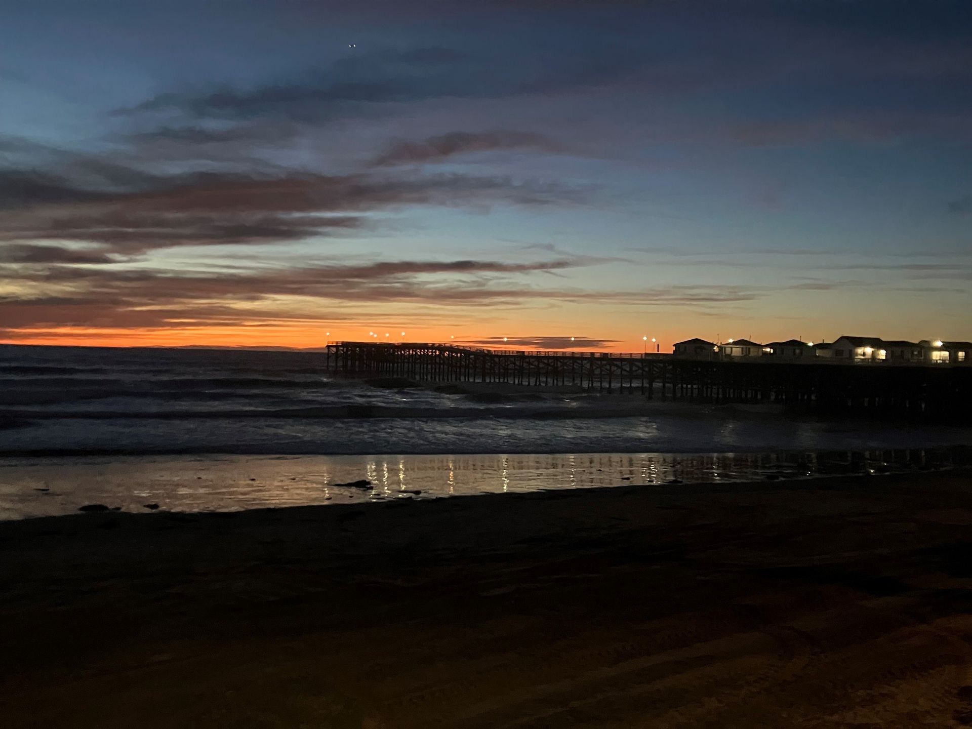 A sunset over the ocean with a pier in the background.