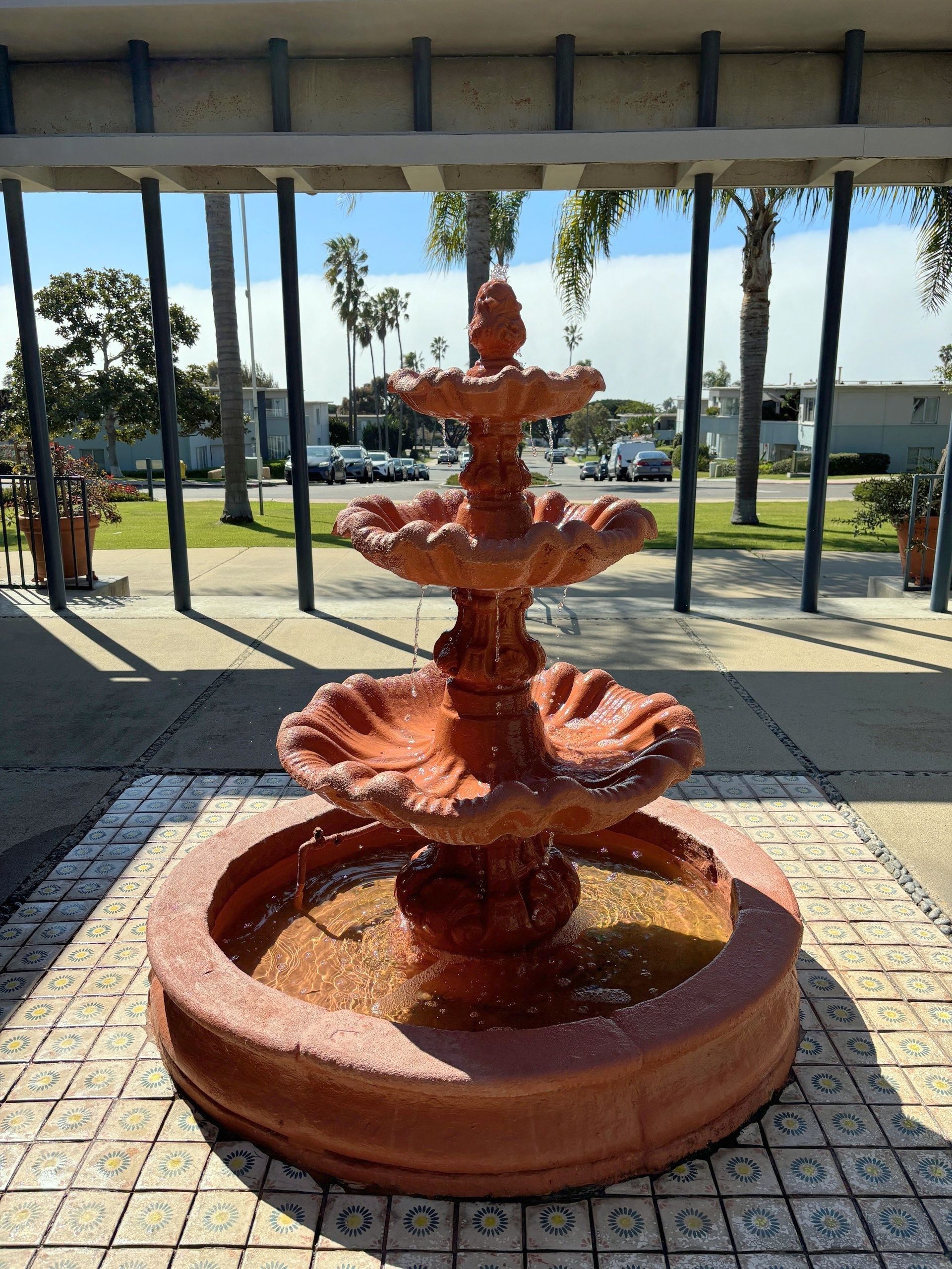 A fountain is sitting on a tiled floor in front of a building.