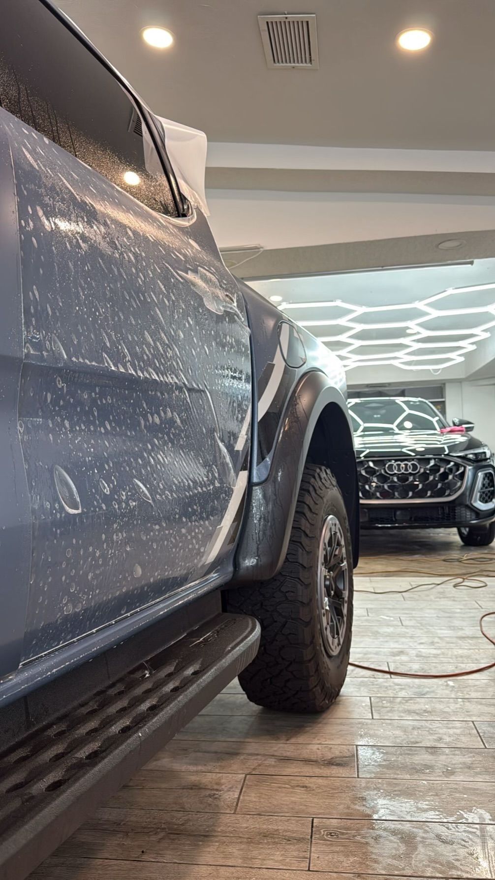 Blue Lamborghini convertible, matte finish, parked inside a garage.