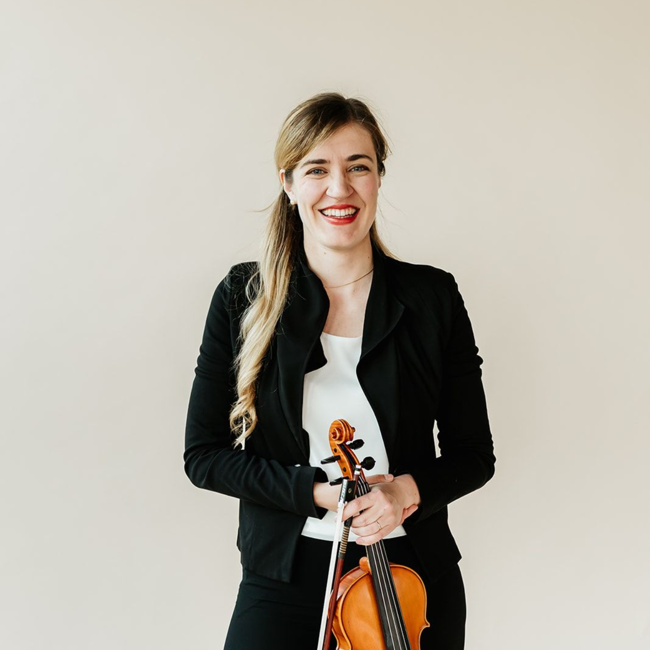 Clara Engen is smiling and holding a violin.