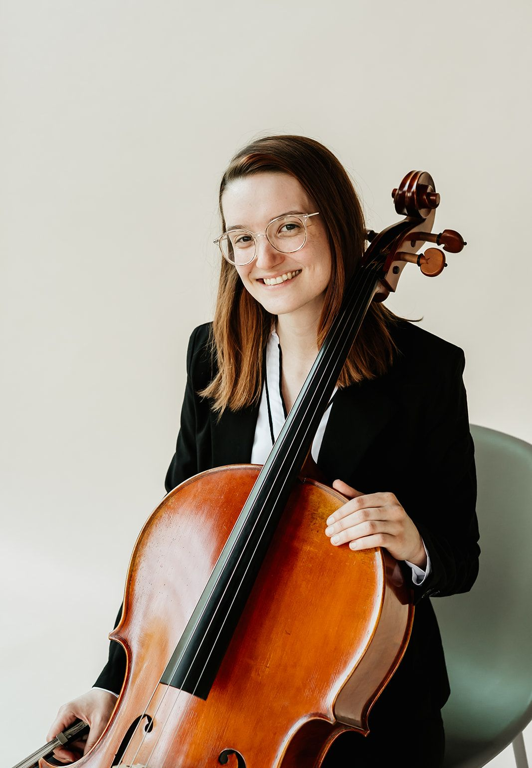 A woman is holding a cello and smiling.