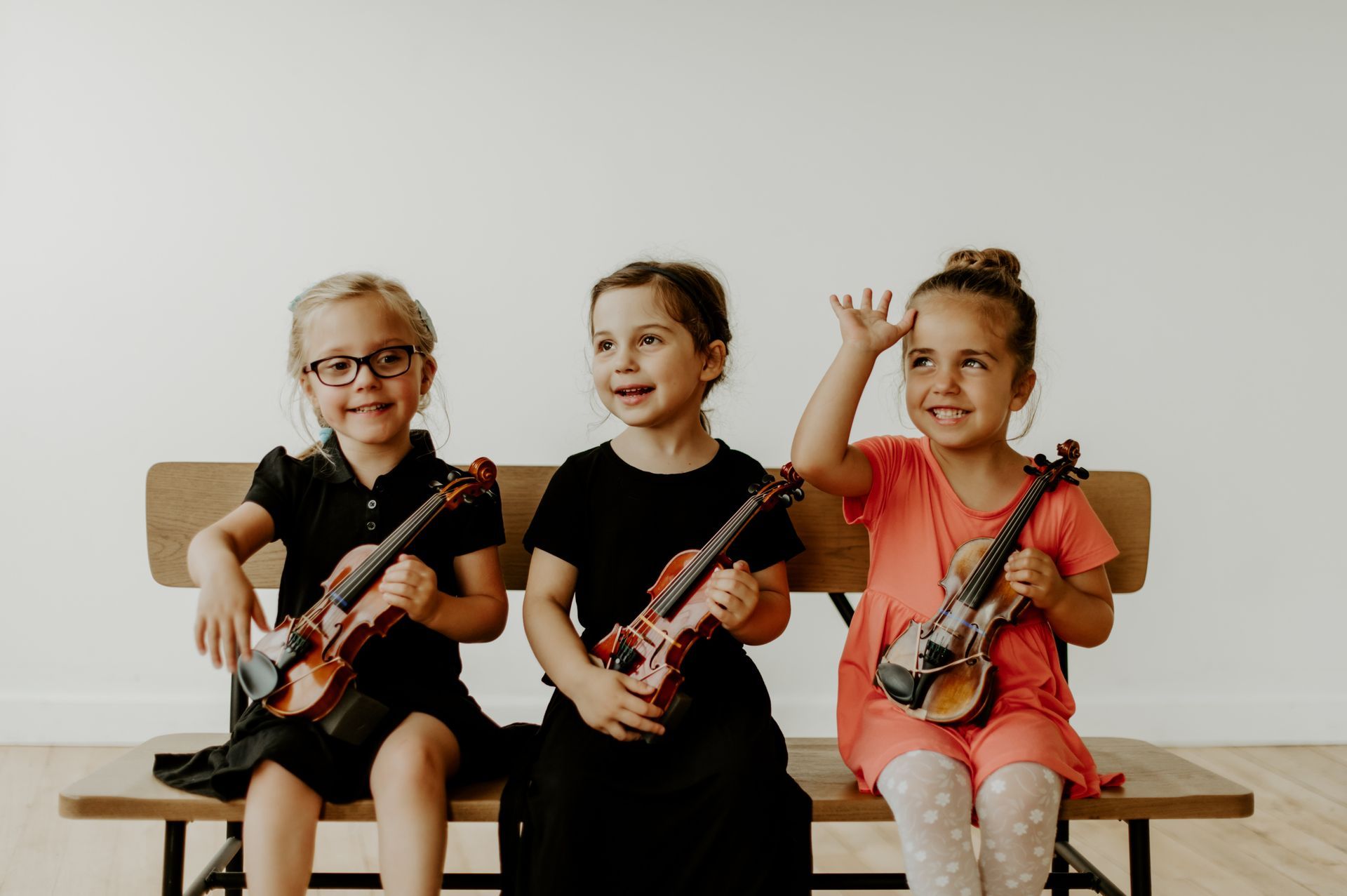 A group of people standing next to each other holding violins and cello.