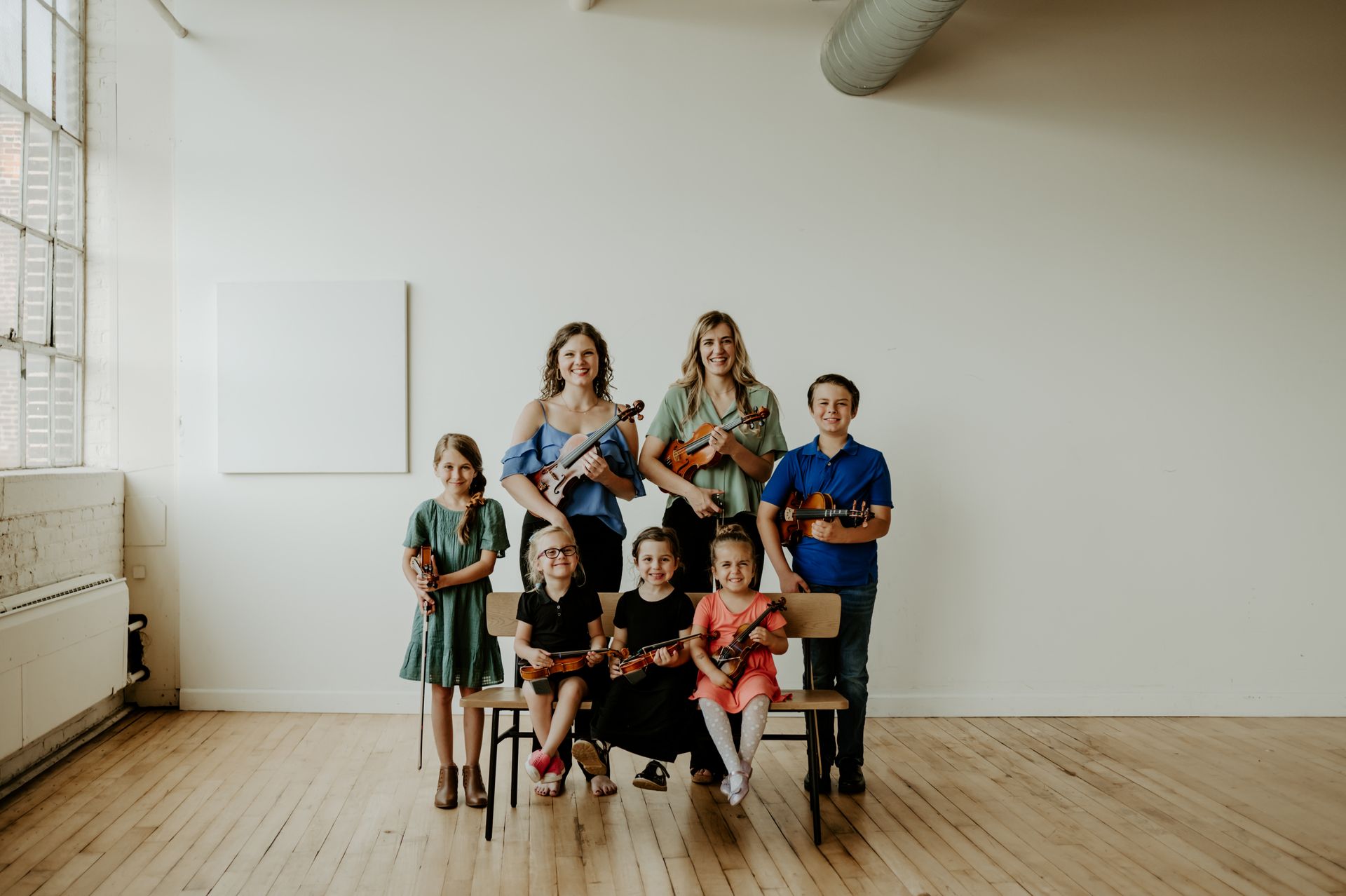 A group of people standing next to each other holding violins and cello.