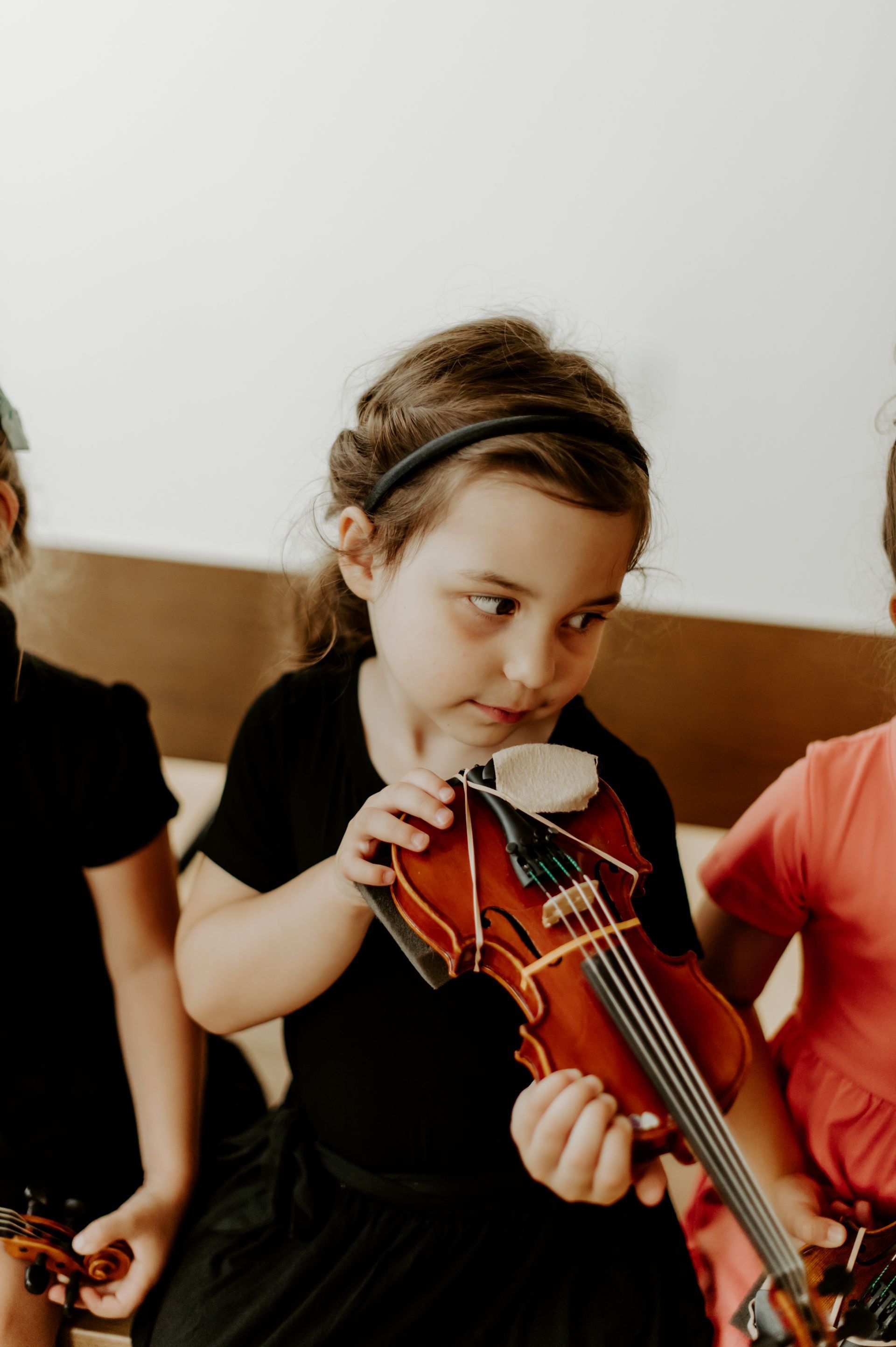 A young girl is playing a violin in a group of children.