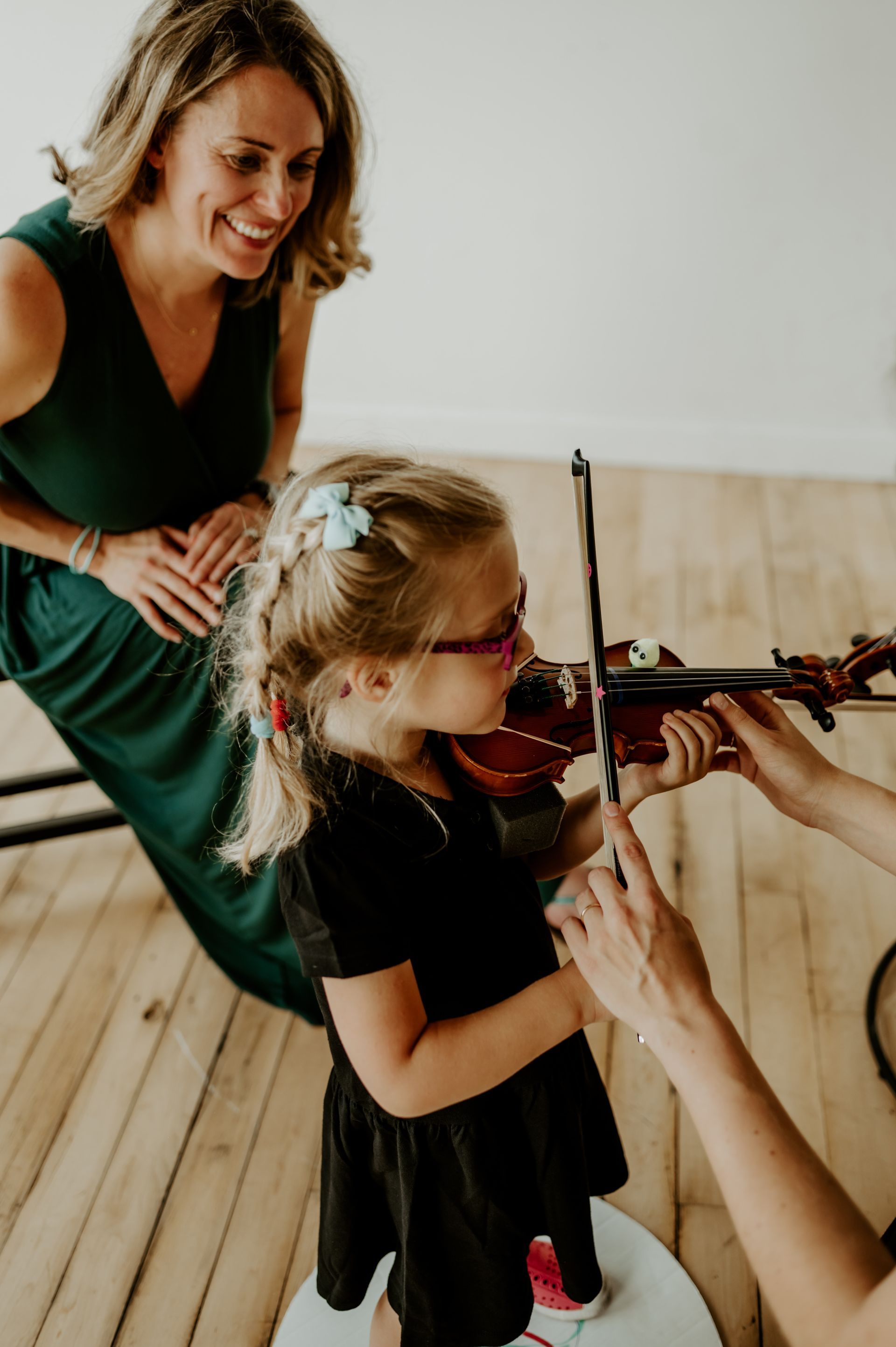 A group of children are standing in a room holding violins.