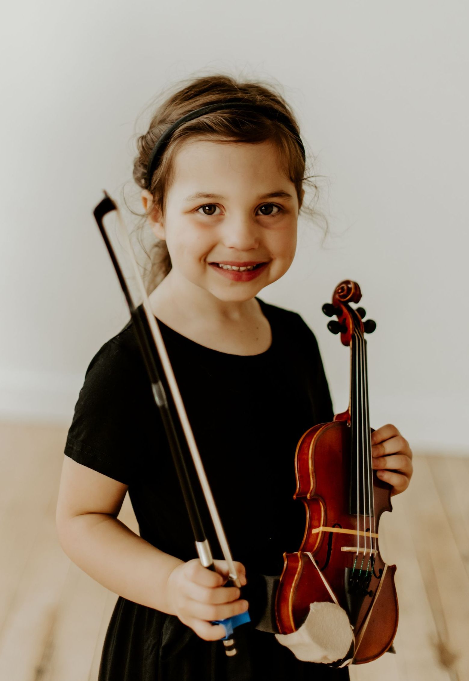 A young girl is holding a violin and bow.