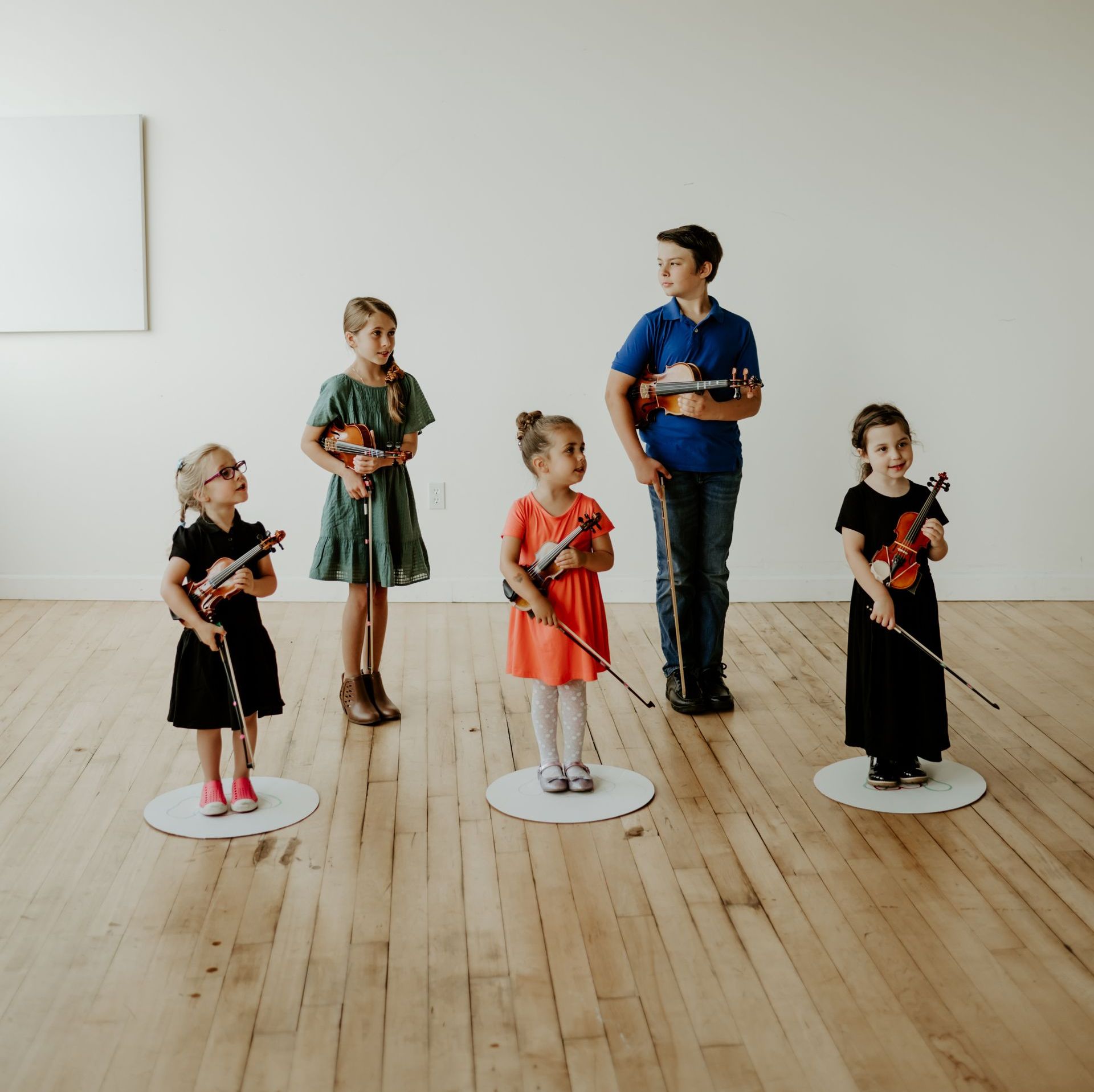 A group of people standing next to each other holding violins and cello.