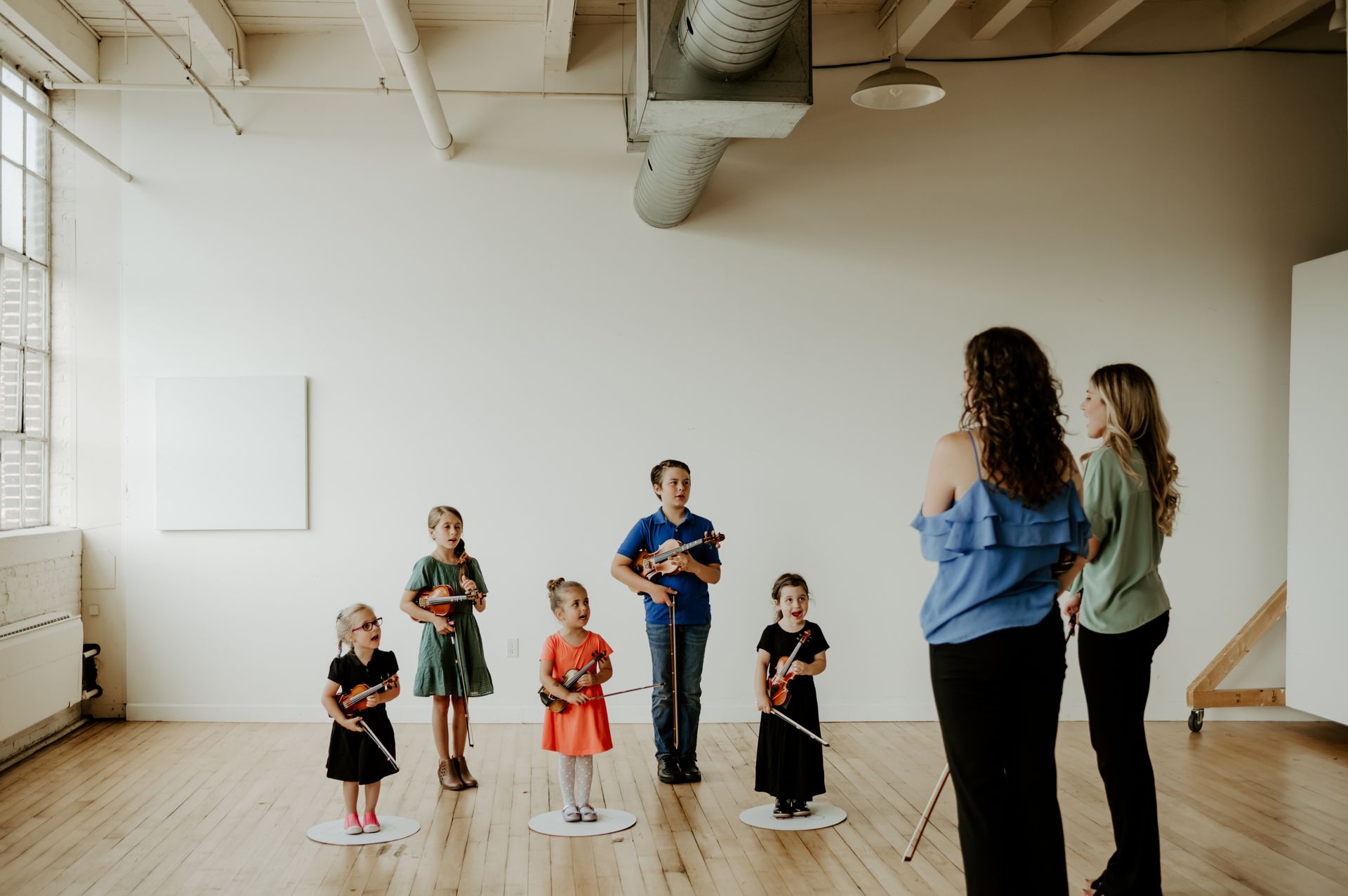 A group of children are standing in a circle holding violins.