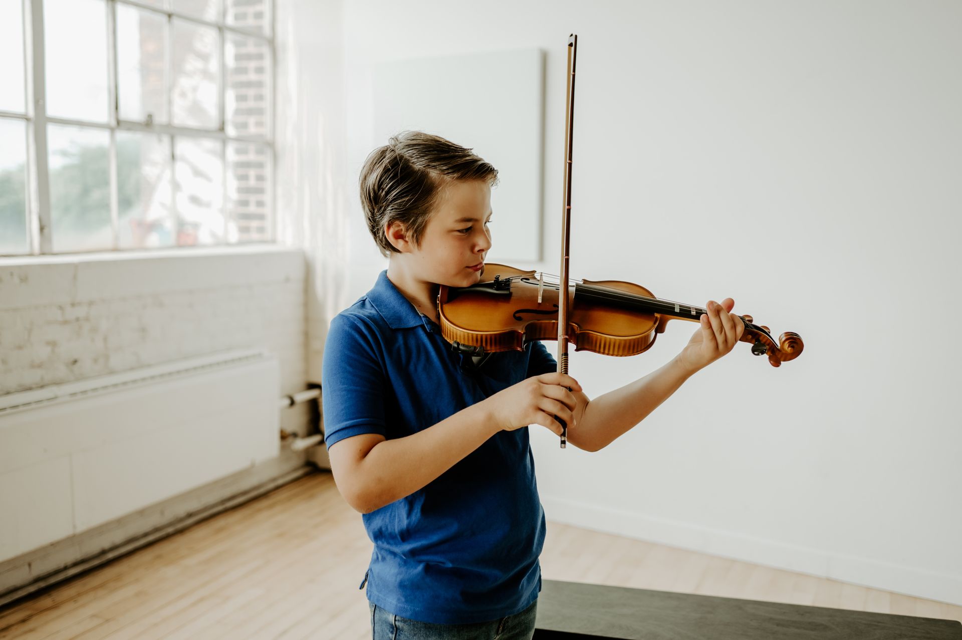 A group of children are playing violins in a classroom.