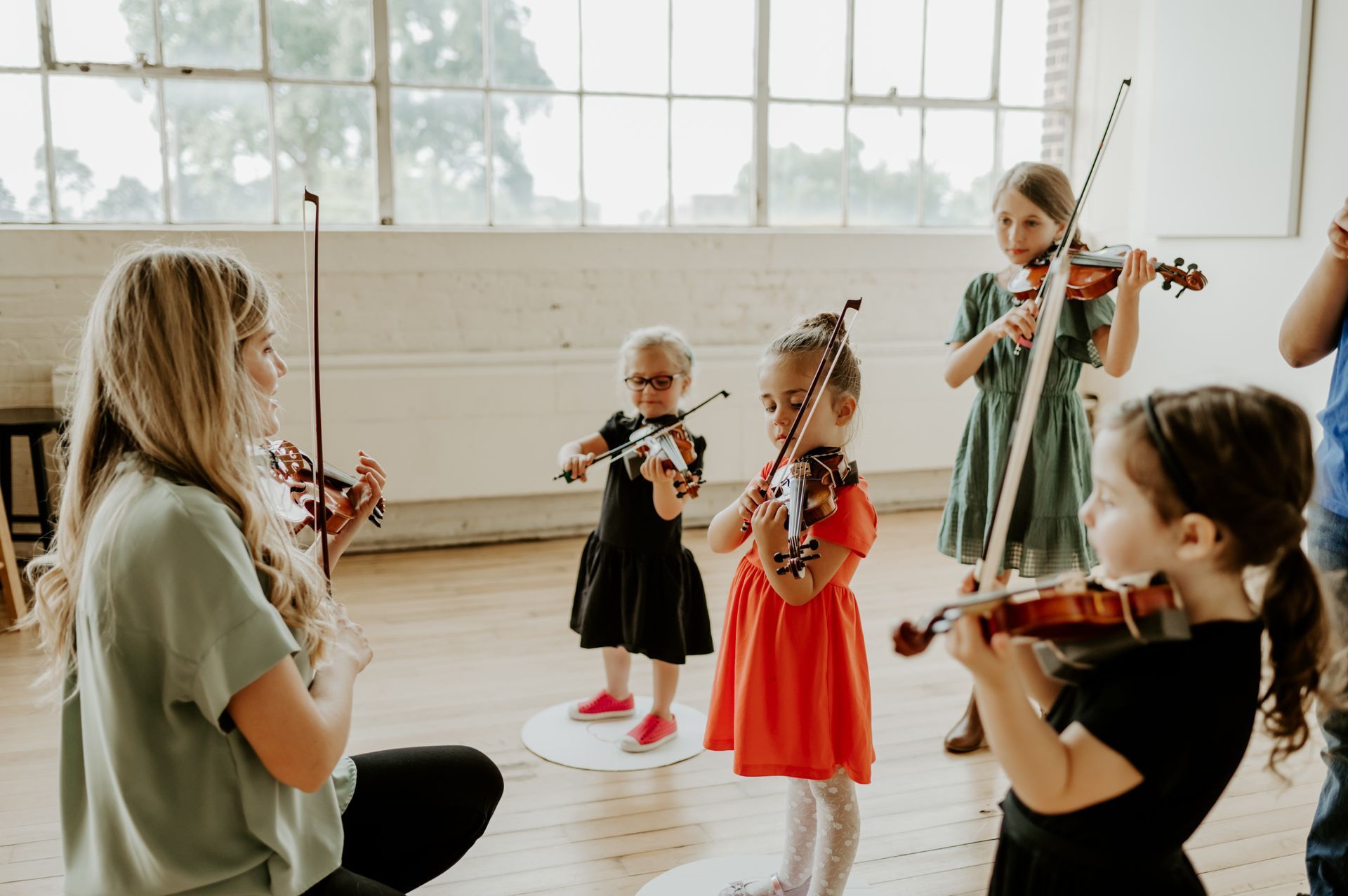 A woman is teaching a group of young girls how to play violins.