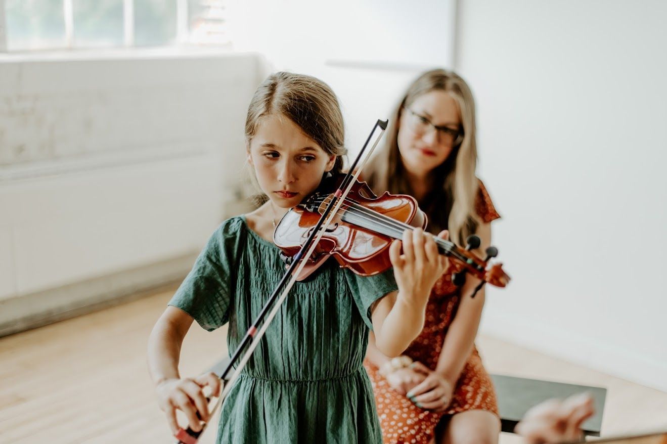 A group of people standing next to each other holding violins and cello.