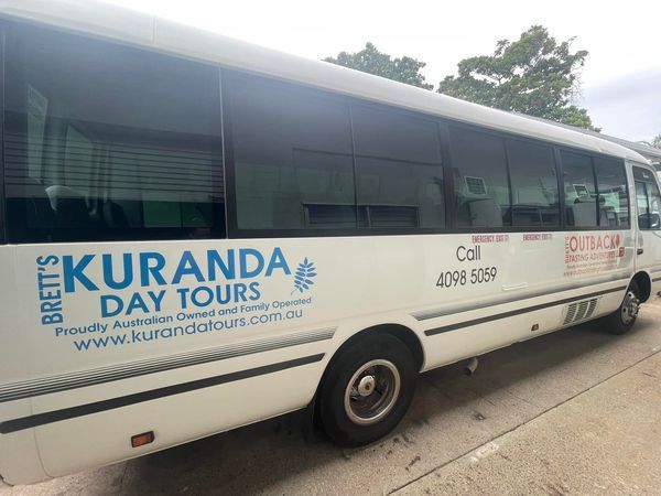 A white bus that says ' brett 's kuranda day tours ' on the side- Sponsorship Signage in Port Douglas, QLD