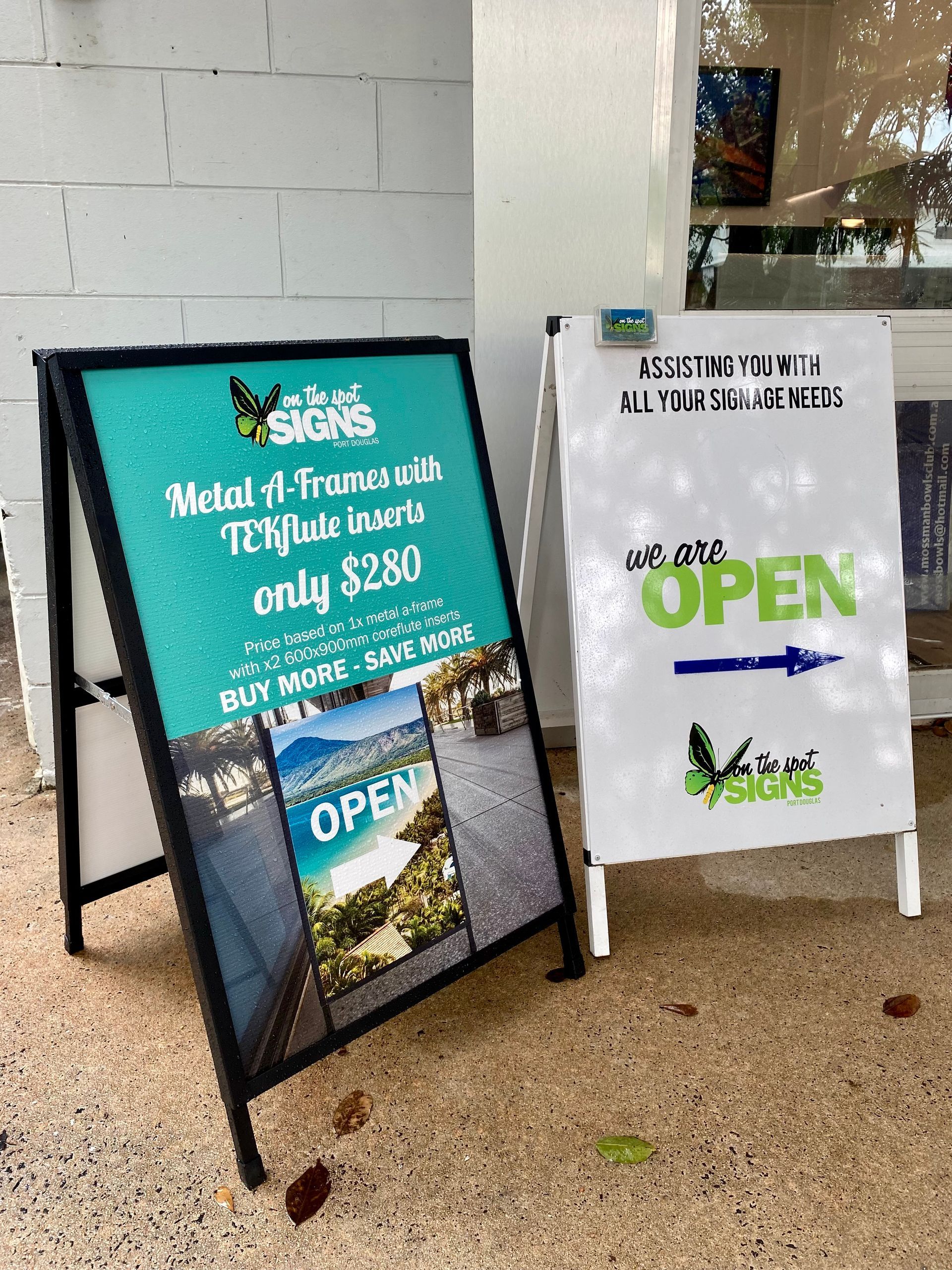 A sign that says `` we are open '' is sitting next to a sign that says `` we are open ''- Sponsorship Signage in Port Douglas, QLD