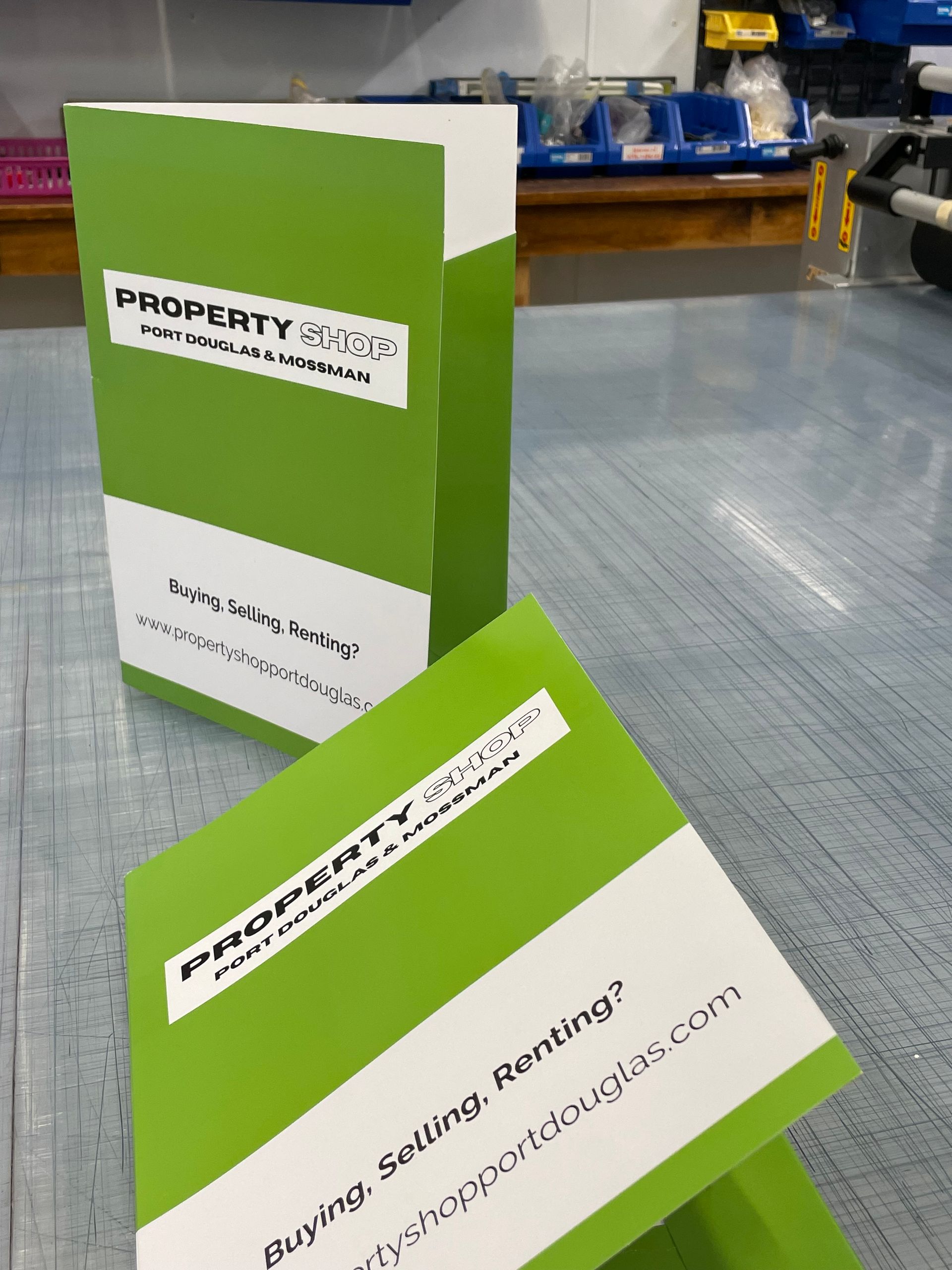 Two green and white folders for property selling and renting- Sponsorship Signage in Port Douglas, QLD