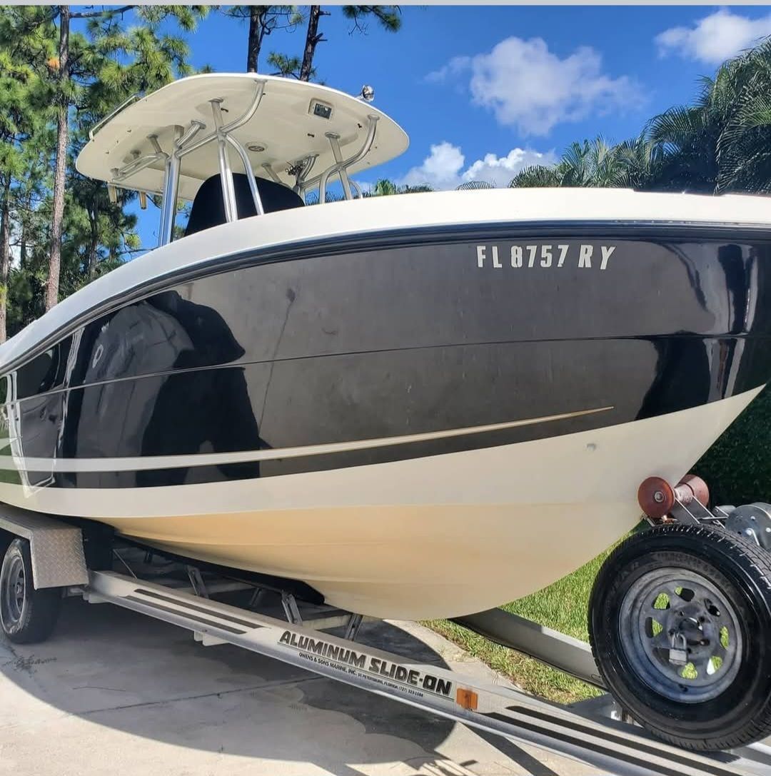 A person wearing black gloves is polishing the hood of a red car.