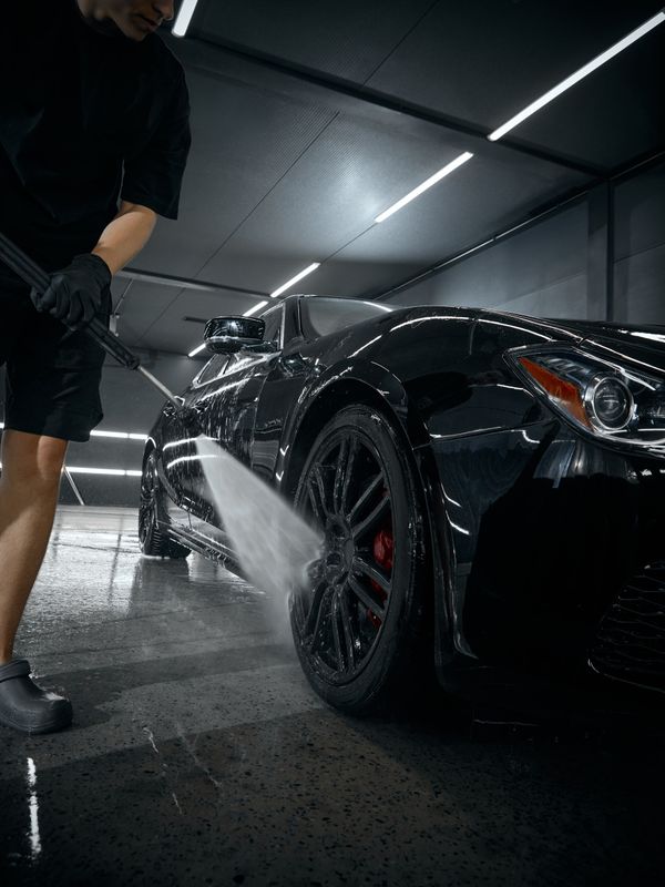 A person wearing black gloves is polishing the hood of a red car.