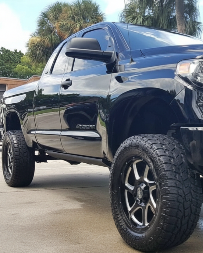 A person wearing black gloves is polishing the hood of a red car.
