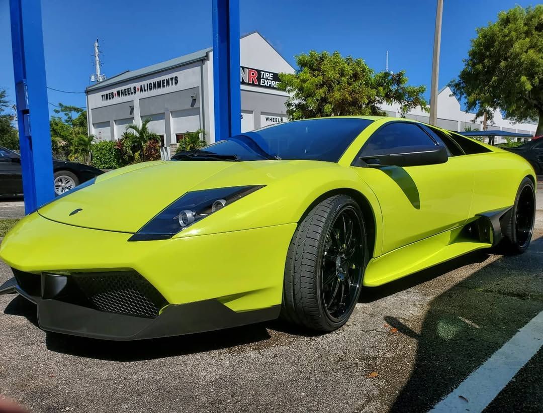 A person is cleaning a blue car with an orange towel
