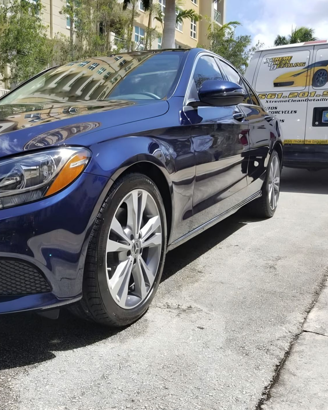A person wearing black gloves is polishing the hood of a red car.