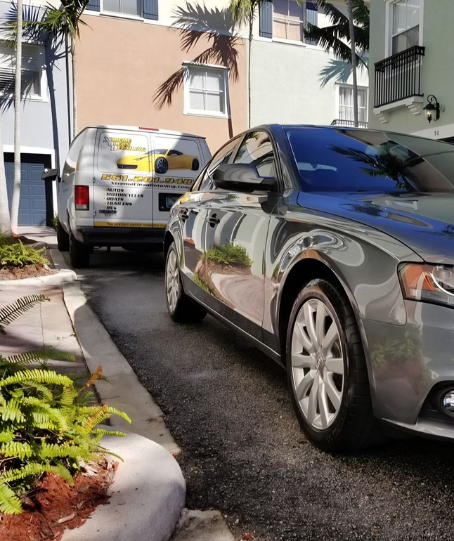 A man is cleaning the wheel of a black car with a sponge.
