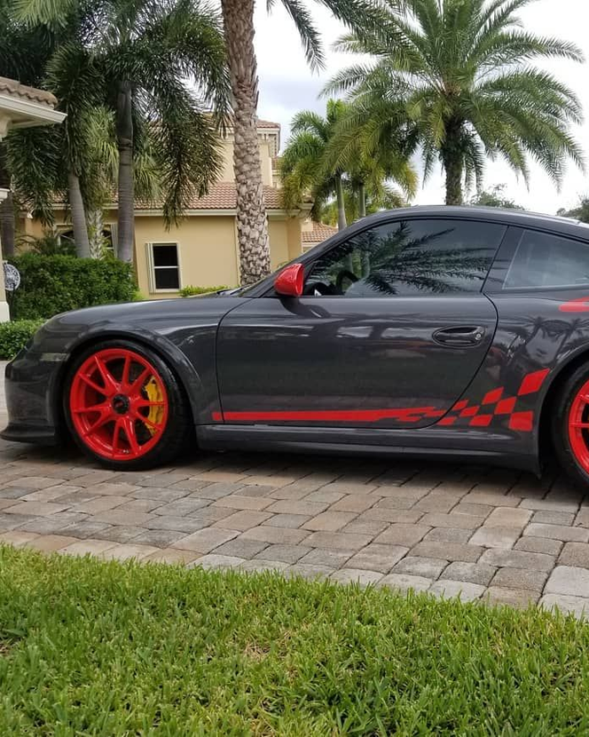 A person is applying a clear film to the hood of a car.
