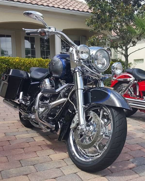 Black and chrome Harley-Davidson motorcycle with custom wheels parked on brick driveway.
