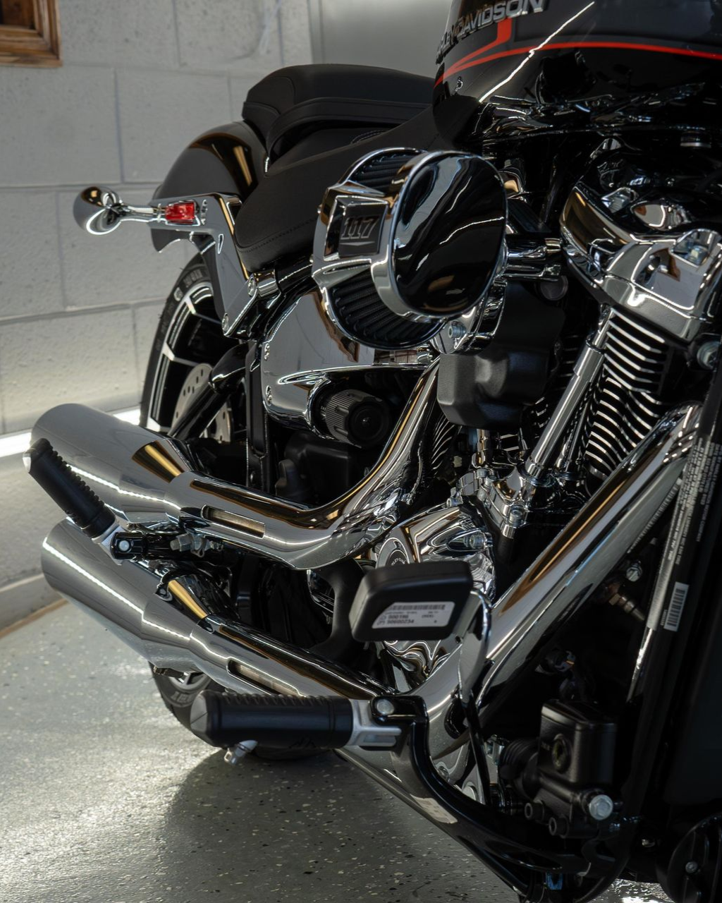 A person wearing black gloves is polishing the hood of a red car.