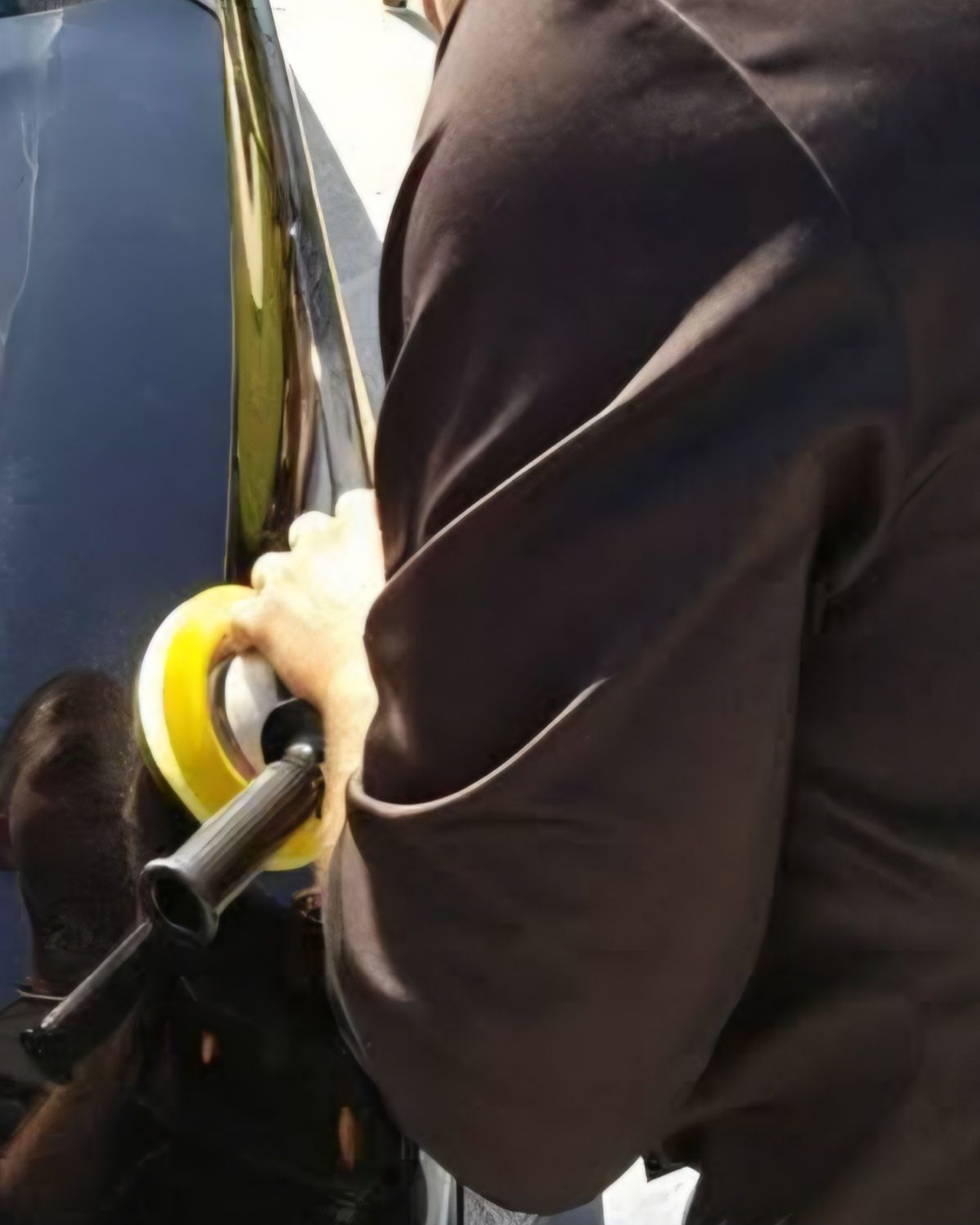 A person wearing black gloves is polishing the hood of a red car.
