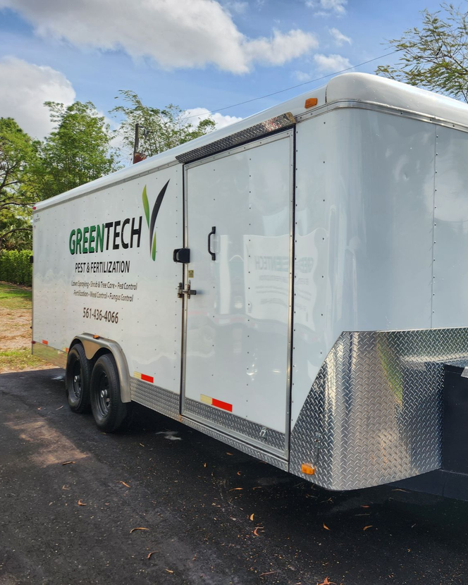 A person is using a blue squeegee to remove plastic from the hood of a car