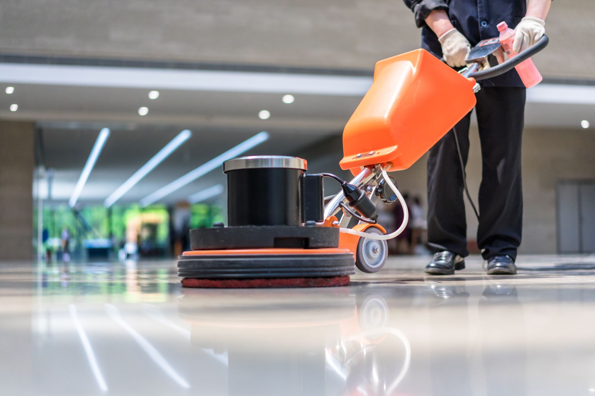 Person using a floor polishing machine in a modern building with reflective flooring. Person using a floor polishing machine in a modern building with reflective flooring.